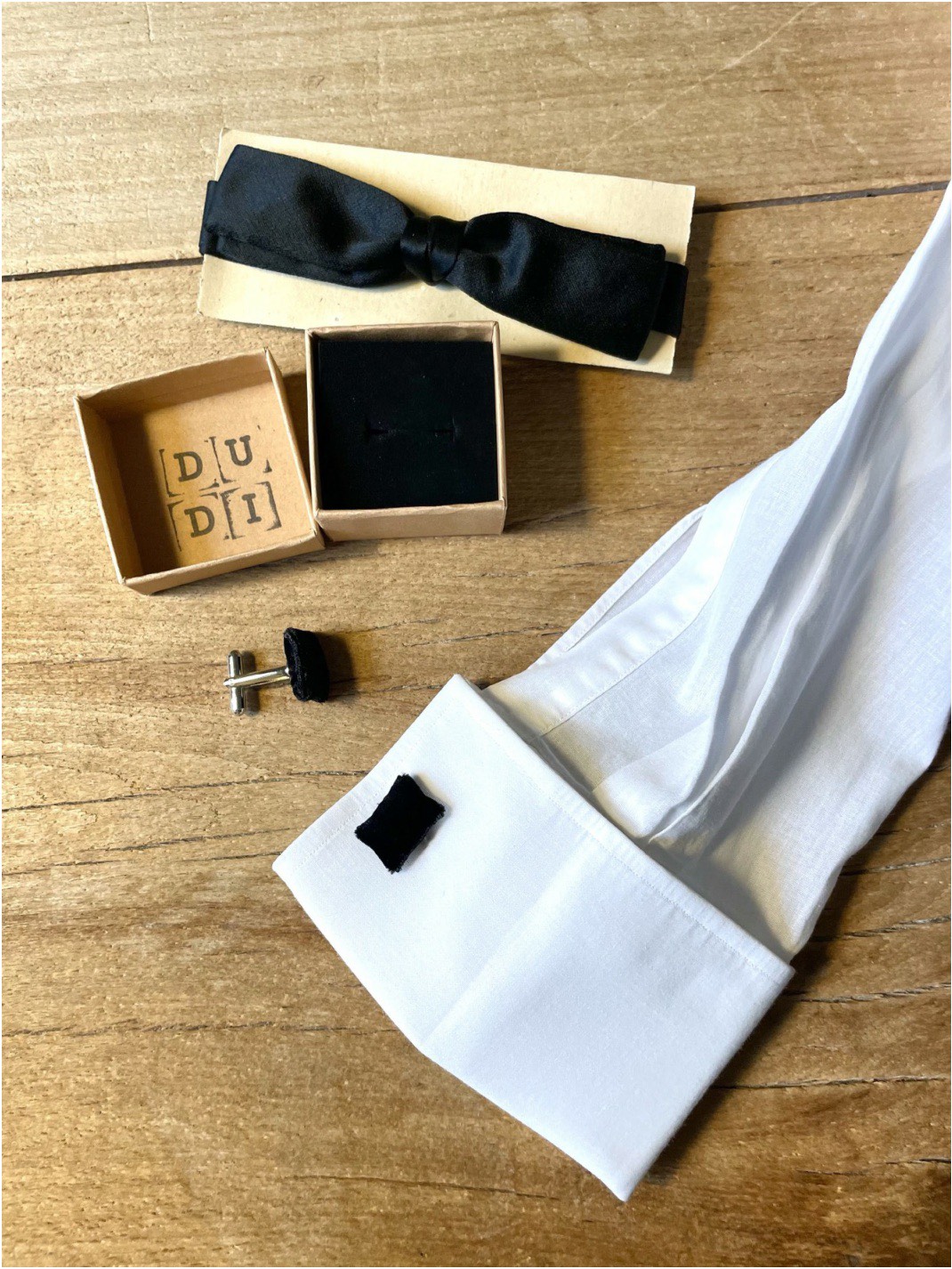 Candy Cufflinks neri accanto a un papillon e a un polsino bianco