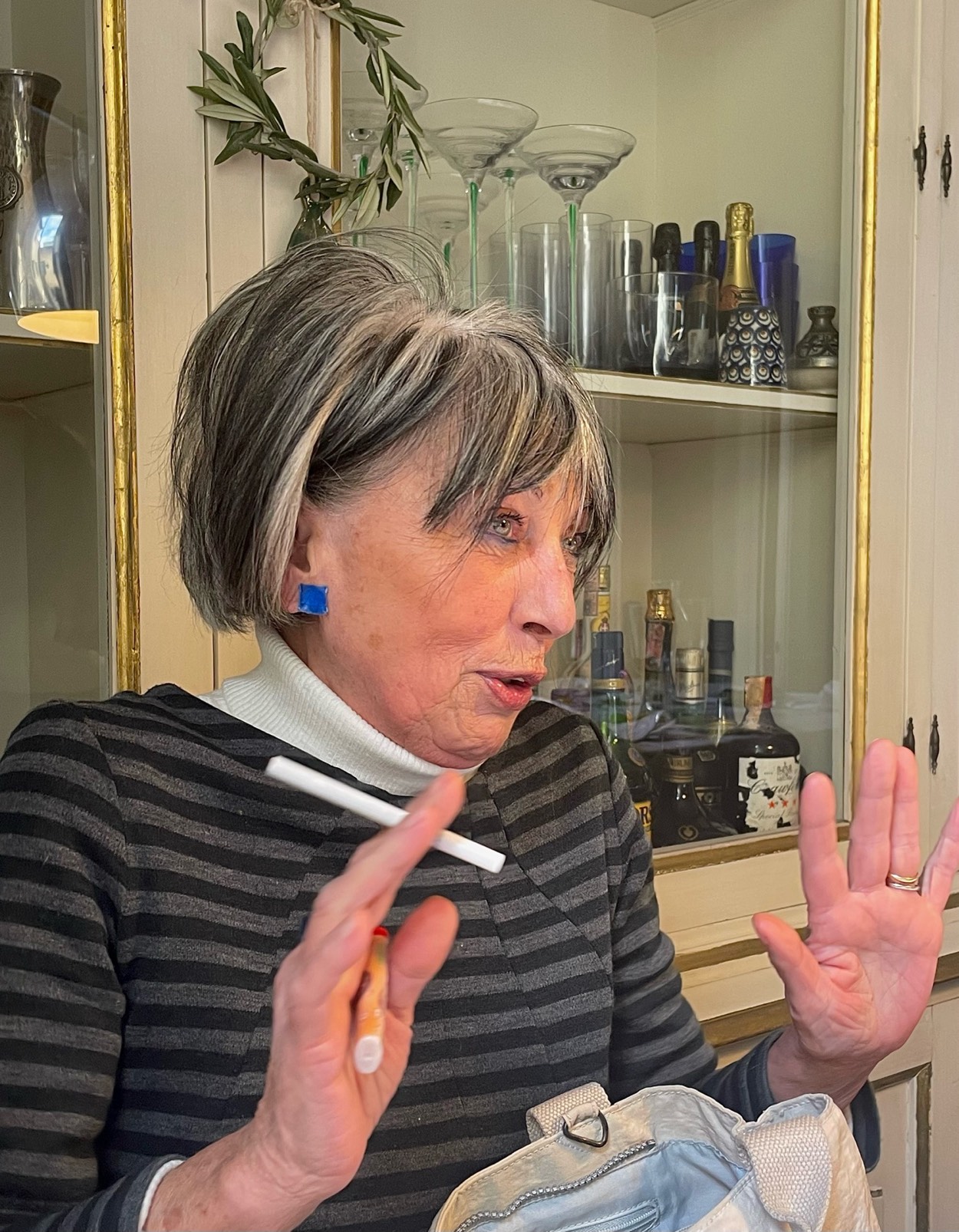 Candy blu indossato in cucina, capelli grigi corti, sigaretta fra le dita