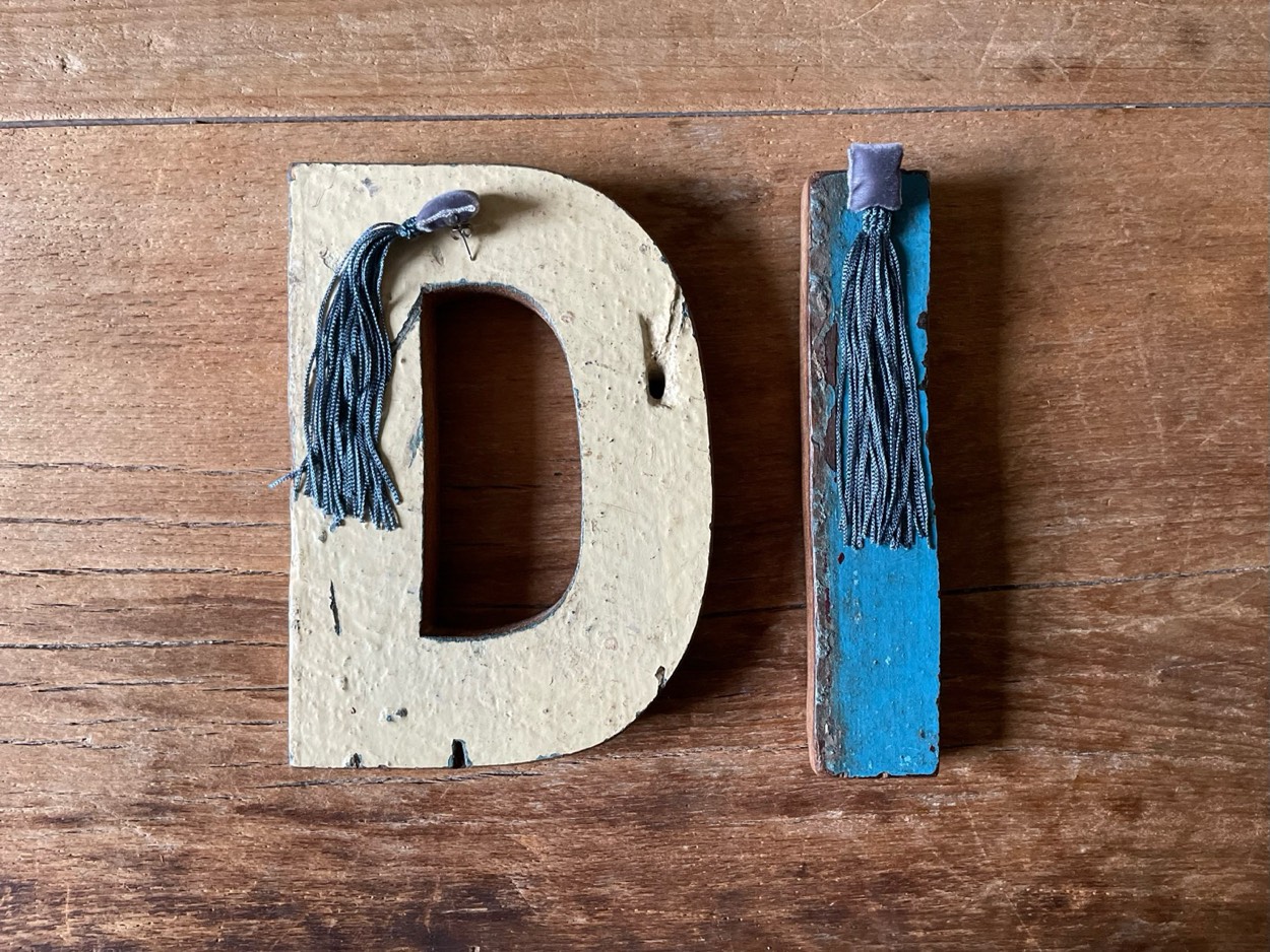 Lettere di legno D e I con frange di seta grigie